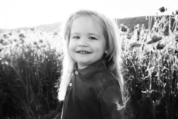 Bambino felice con bionda lunga in campo di fiore di primavera di papavero. Infanzia e felicità. Emozioni dei bambini. Faccia buffa di bambino sorridente. — Foto Stock