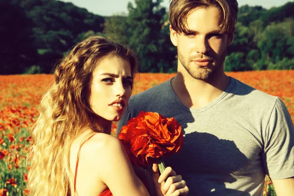 Spring couple with flower bouquet in field of poppy, couple in love. Horny hot young people embracing.