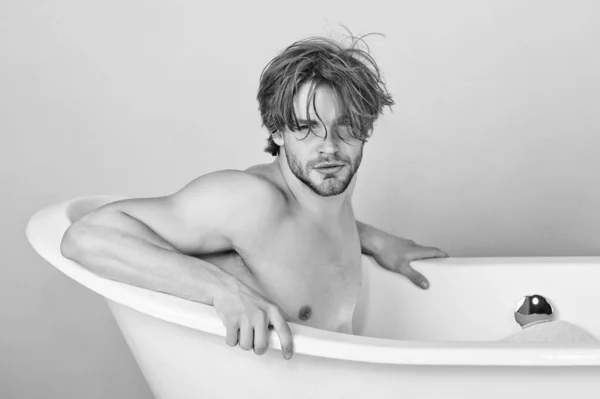 Sexy mladý muž se svalnatým tělem sedící ve vaně. Chlápek ve vaně. Lázně a krása, relaxace a hygiena, zdravotní péče, kopírovací prostor. Černá bílá. — Stock fotografie