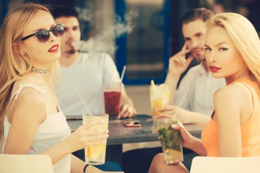 Restorandaki arkadaşlar. Gençler akşam yemeği için restoranda oturuyor ve içecek olarak kuyruk sallıyorlar..