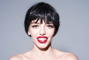 Çekici kırmızı dudaklı kadın kameraya bakıyor. Güzel gülümseme konsepti. Çıplak omuzlarıyla poz veren mutlu yüzlü bir kız..