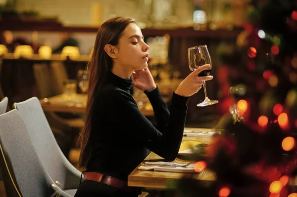 Женщина любит вино в ресторане. Концепция зимних праздников. Девушка празднует Новый год и Рождество. Праздничная мода, стиль, украшения. Вечеринки. — стоковое фото