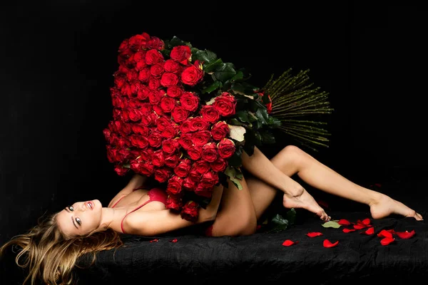 Seksowna zmysłowa kobieta z bukietem róż. Dziewczyna w czerwonej bieliźnie z Valentines obecny. — Zdjęcie stockowe