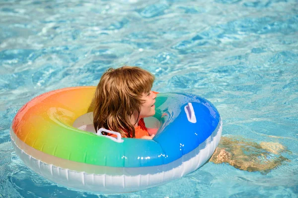 Zomervakantie. Een jongen in een zwembad. Kind in het aquapark. Grappige jongen op opblaasbare rubberen cirkel. — Stockfoto
