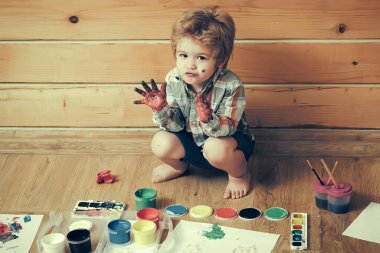 Ahşap zeminde boyacı çocuk. Hayal gücü, yaratıcılık ve özgürlük kavramı. Renkli elleri, gouache resimleri ve çizimleri olan bir çocuk. Sanat ve zanaat..