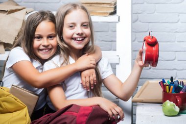 Çocukluk ve mutluluk kavramı. Okul sınıfında saati olan mutlu küçük kızların mutlu çocukları. Özel okul, komik öğrenciler..