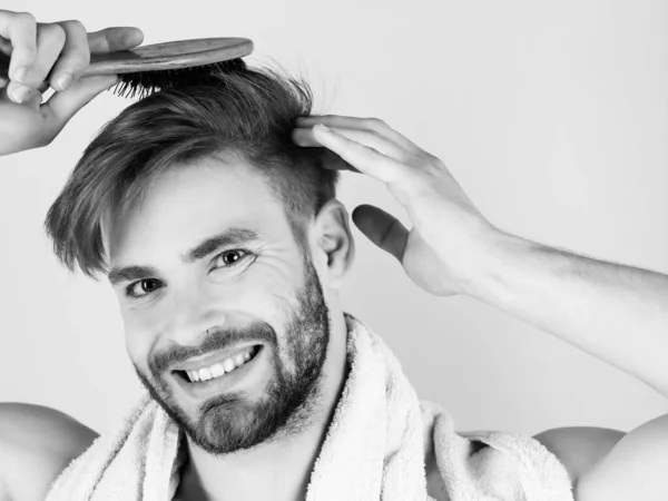 Άνδρας που χτενίζει υγιή μαλλιά με βούρτσα σε δυνατά χέρια. Ανδρική περιποίηση και υγιεινή. Σαλόνι ομορφιάς. — Φωτογραφία Αρχείου