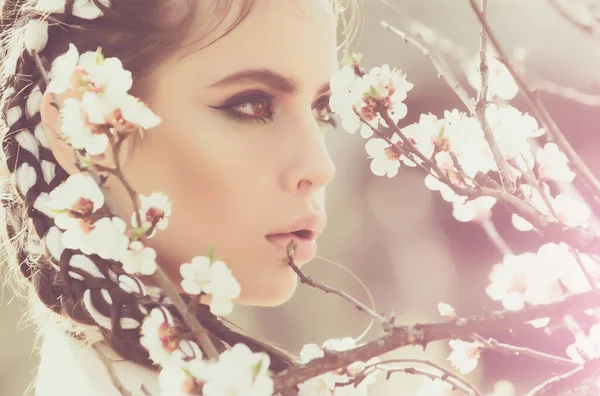 Frühlingsmädchen und Blumen. Hübsche Frau mit blühenden Blumen, modisches Make-up im Gesicht, im Freien, natürlicher Hintergrund. — Stockfoto