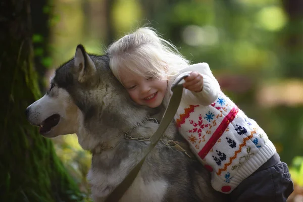 Szczęśliwa dziewczynka ze swoim psem husky. Szczęśliwe dziecko i pies przytula się z czułością uśmiechając. Pozytywne emocje dzieci. Szczęśliwego dzieciństwa. — Zdjęcie stockowe