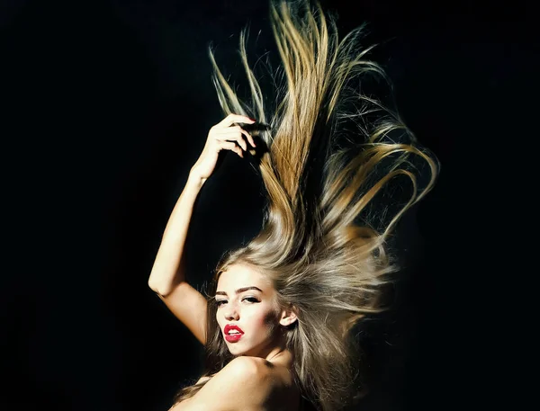 Όμορφη νεαρή γυναίκα μοντέλο με μακριά πλούσια μαλλιά φτερουγίζει στον άνεμο γυμνό πίσω στο στούντιο σε μαύρο φόντο. — Φωτογραφία Αρχείου