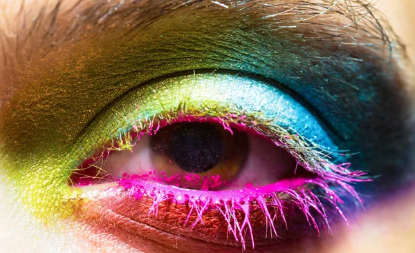 Eye with colorful neon paint fashion makeup. Holi, paint party, colors festiva.
