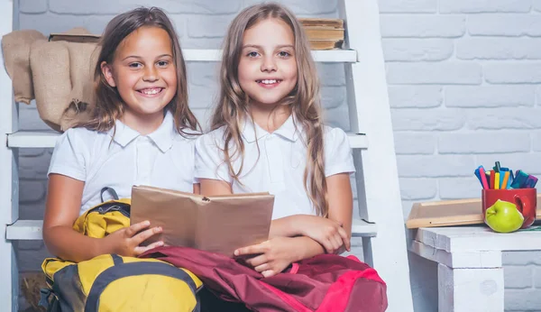 Schoolgirls studying homework during her lesson at home. Story reading in book at two small girls. Learning and education. — Stock Photo, Image