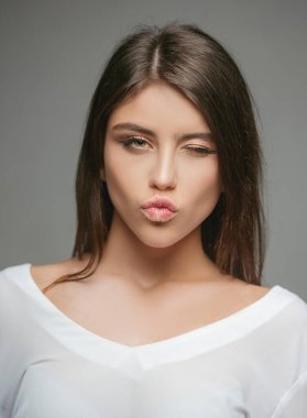 İnsanların duyguları. Mutlu genç kadın göz kırpıyor ve öpüşüyor. Şirin kız portresi..