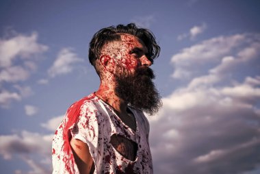 Yüzü kanlı, yırtık tişörtlü zombi hippi. Cadılar Bayramı şeytanı ve dehşeti. Kırmızı kanlı sıçrayan bir adam. Savaş askeri ya da kurban konsepti.