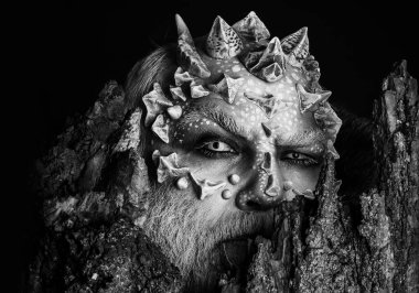 Siyah arka planda yaşlı ağaç kabuğunun arkasındaki şeytan. Ejderha derili ve sakallı bir adam. Keskin dikenli ve siğilli bir canavar. Ağaç ruhu ve fantezi kavramı.