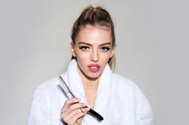 Çekici dudakları olan kadın jileti elinde tutuyor. Berber dükkanı konsepti. Kadın keskin jiletle oynuyor..