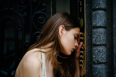 Depresyondaki üzgün kadın. Kendini soyutlama. Ev güvenliği kavramı. Kadın dahili iletişim kodu düğmesi. Bayan kadın kapı zili bina girişinde..