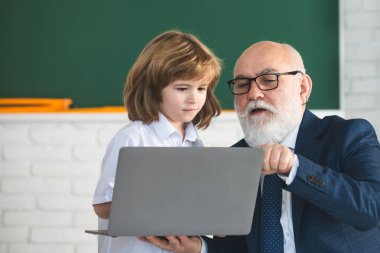 Okula dönelim. Bilgisayarlı öğretmen ve çocuk. Çevrimiçi eğitim ve öğrenme kavramı. Öğrenci çocuk sınıfında. Yaşlı öğretmen ve genç öğrenci..