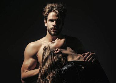 Kaslı gövdeli ve şehvetli bir kadın. Siyah arka planda aşık bir çift. Güzellik, moda konsepti.