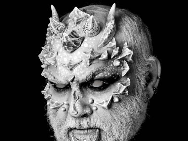 Ejderha derisi ve gri sakallı bir şeytan. Yüzünde sivri dikenleri ve siğilleri olan şeytani bir canavar. Korku ve fantezi konsepti. Siyah arkaplanda iblis kafası.