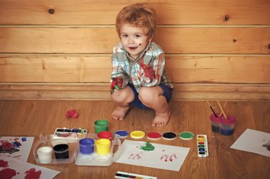 Renkli elleri, gouache resimleri ve çizimleri olan bir çocuk. Çocuk oynuyor. Hayal gücü, yaratıcılık ve özgürlük kavramı. Çocuk sanatları ve el sanatları. Ahşap zeminde boyacı çocuk..
