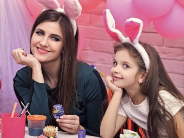 Mutlu Paskalyalar. Tavşan kulaklı anne ve kız. Tatile hazırlanıyorlar..