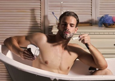 Genç çekici bir adam aynada tıraş olur, banyoda bornozla tıraş olur..