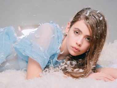 Pijamalı kadın dinleniyor. Yumuşak ve nazik bir kavram. Sakin yüzlü kız, kuş tüyü ve tüylerle kaplı yatağa uzanıyordu..