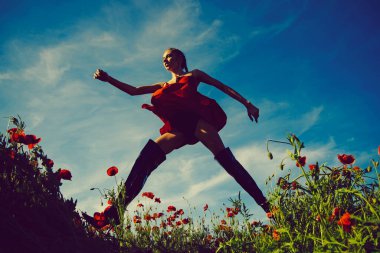 Kırmızı çiçek tarlasında atlayan bir kadın, moda yazı..