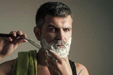 Berber dükkanındaki hippi. Adam tıraş fırçası ve tıraş bıçağıyla sakal ve bıyık kesti. Sakallı adamın saç kesimi. Berber ve kuaför. Moda ve güzellik.