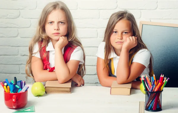 Bored school kids at lesson. Back to school and home schooling. Friendship of small sisters in classroom at knowledge day. Little girls eat apple at lunch break. — Stock Photo, Image