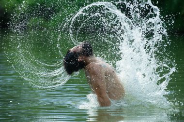 Islak saçlı, sakallı, suda yüzen seksi sakallı adam. Islak saçlarından ve sakalından su sıçrayan geyler eğleniyor. Özgürlüğü hisset.