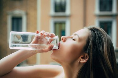 Su içen kadın. Açık havada şehvetli genç bir kız. Susuz kalma. Şehir portresi. Moda ve güzellik. Lüks sokak tarzı moda..