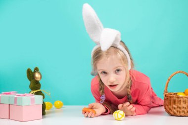 Paskalya yumurtası boyalı çocuk. Şaşkın kız bahar tatilinde tavşan kulağı takıyor. Kutlama dekorasyonu, sembol, gelenek, kutlama, hazırlık.