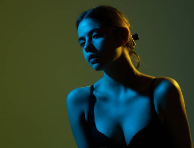 Sütyen giyen seksi mavi neonlu kız yeşilde izole edilmiş. Siyah sütyenli kadın memesi. Seksi göğüslü kız. İç çamaşırlı, doğal seksi göğüslü bir kadın..