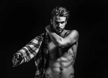 Dağınık saçlı, esmer arka planda ekose gömlek giyen seksi, genç, çıplak bir adam. Baştan çıkarıcı gay.