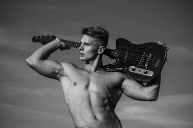 Gövdesi kaslı bir adam gitarı tutuyor. Müzik, performans, eğlence. Sporcu gitarist.