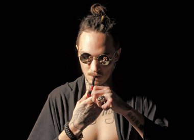 Siyah arka planda pipo içen ciddi bir adam. Güneş gözlüklü sigara içen adam. Kötü alışkanlıklar, nikotin bağımlılığı. Sağlıksız yaşam tarzı kavramı.