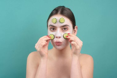 Güzellik tedavileri. Yüz maskesi. Cilt bakımı. Yüzünde salatalık dilimleri olan bir kadın..