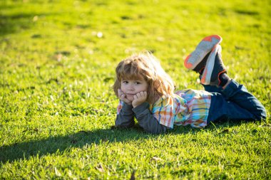 Çimlerin üzerinde yatan çocuk. Çocuk yaz yürüyüşü. Çocuk adaptasyonu. Yaz havası.