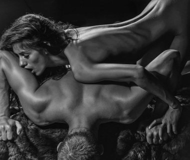 Yatakta yakışıklı, kaslı bir adamın üzerine uzanmış oldukça zayıf, seksi bir çift kadın..