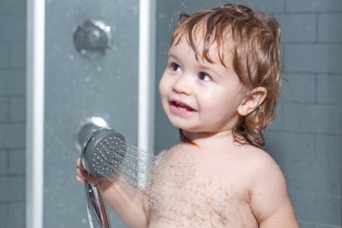 Komik, mutlu bebek küvette su ve köpükle yıkanır. Duşun altında yıkanan çocuk. Çocuk hijyeni..