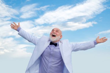 Tasasız bir hayat kazanan olgun bir adam. Beyaz takım elbiseli klasik başarılı erkek gökyüzünde eğleniyor..