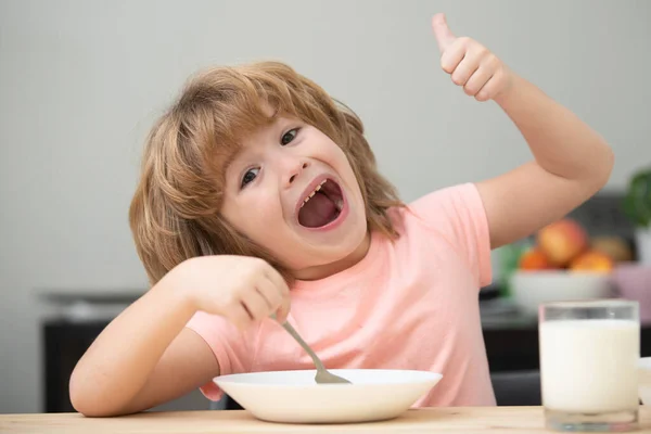 かわいい子供がスプーンで自宅でテーブルのそばで昼食を取るスープの食事や朝食を食べている肖像画。子供の健康食品. — ストック写真
