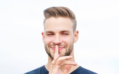 Dudaklarında parmak olan ciddi bir adam. Komplo mu? Tecrit edilmiş çekici erkek sessizlik işareti gösteriyor.