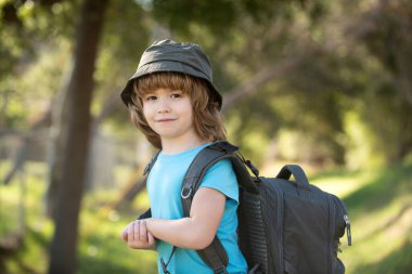 Sırt çantalı küçük bir çocuk manzaralı dağlarda yürüyüş yapıyor. Çocuk yerel bir turist yerel bir yürüyüşe çıkıyor.