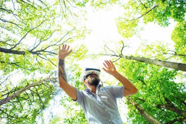 VR gözlüklü adam dijital dokunmatik ekran kullanıyor. Kablosuz gözlüklü hippi hayali gerçekliği keşfederken havada jestler yapıyor..