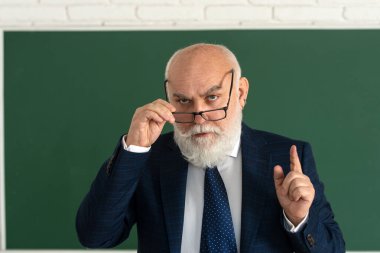 Ders sırasında kurusıkı tahtada yaşlı bir öğretmen, üniversitede öğretmenlik yapıyor. Eğitim ve bilgi kavramı. Akademik başarı.