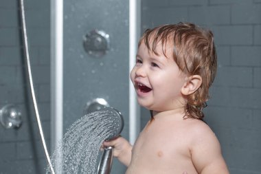 Duşun altında yıkanan çocuk. Küçük bebek saçını banyoda yıkıyor..