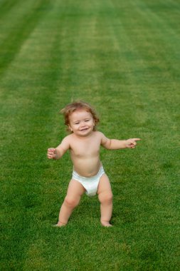 Şirin, komik, gülen bebek emeklemeyi öğreniyor çimlerde oynayıp, bahçede yazı izlerken eğleniyor. Bezi olan küçük eğlenceli bir çocuk..